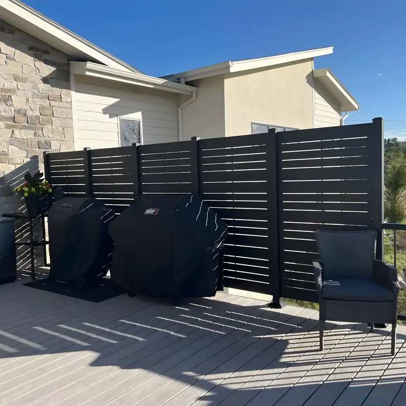 Deck with a horizontal slat privacy wall behind grills and a chair
