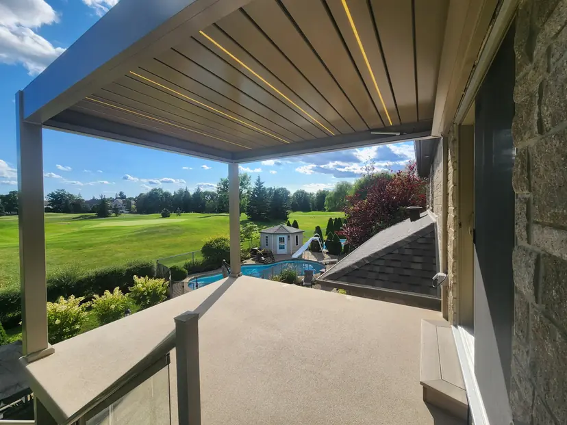 Louvered roof with lit blades over a patio with a golf course view