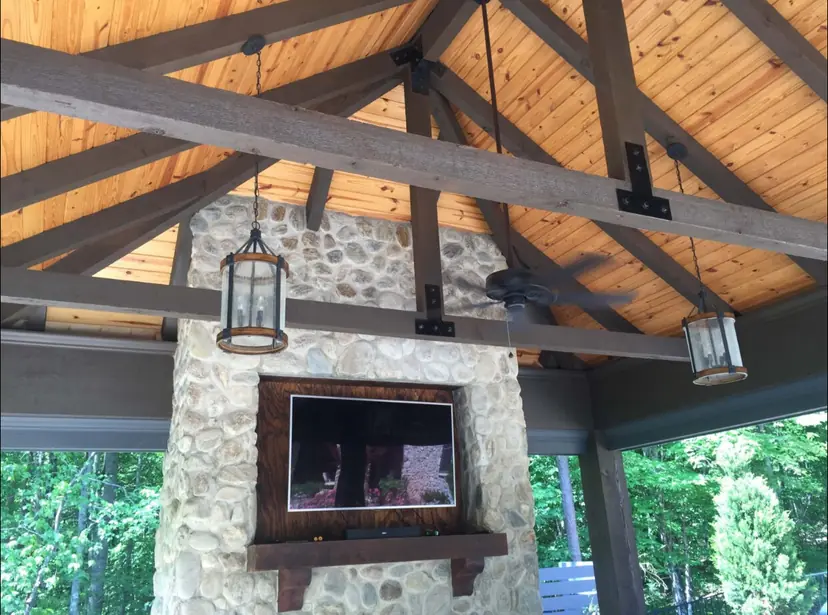 Cabana interior with a cedar ceiling, timber trusses and a stone fireplace