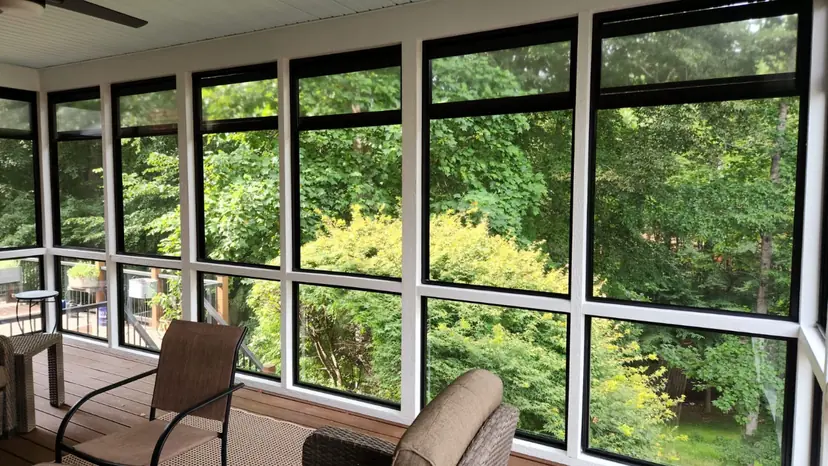 Screened porch interior with framed screens, chairs and a view of the trees