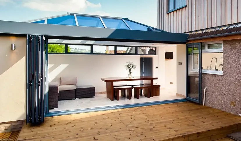 Dark-framed bi-fold doors folded flat against one side, opening a room onto a wood deck