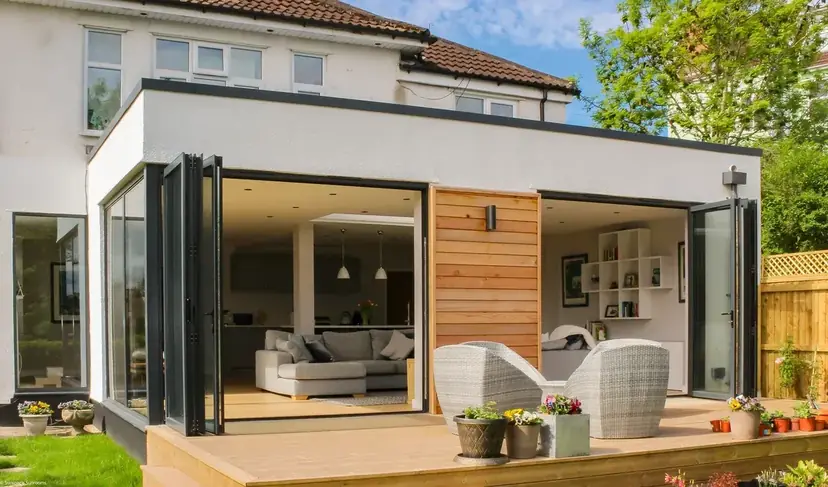 Home addition with bi-fold doors folded open at both corners onto a deck