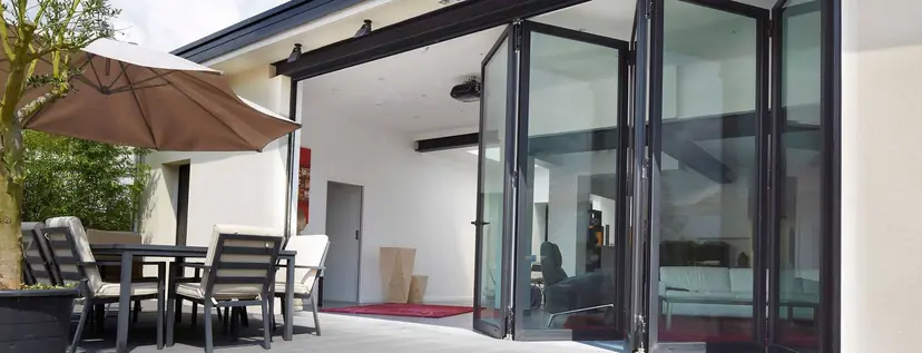 WeatherMaster Plus bi-fold doors stacked open onto a patio with a dining table