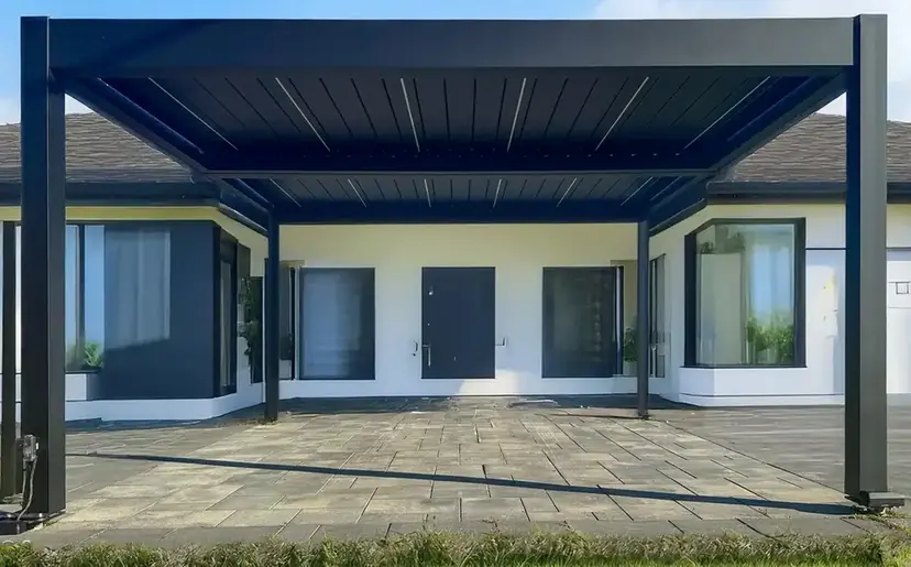 Sunspace louvered pergola standing on a stone patio in front of a home