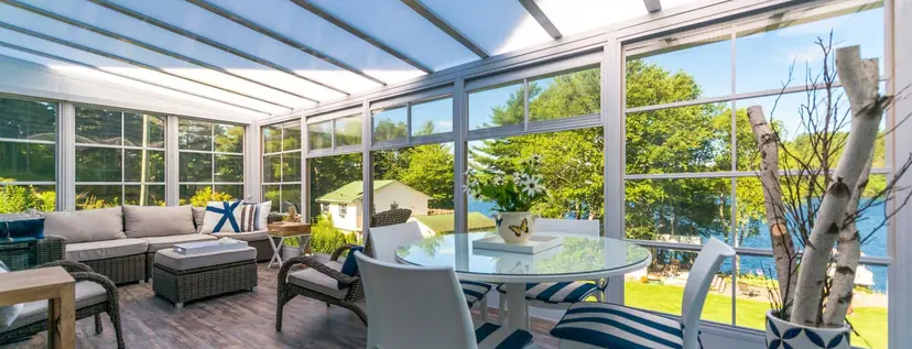 Sunspace Model 200 sunroom with a glass roof and wall of windows beside a lake