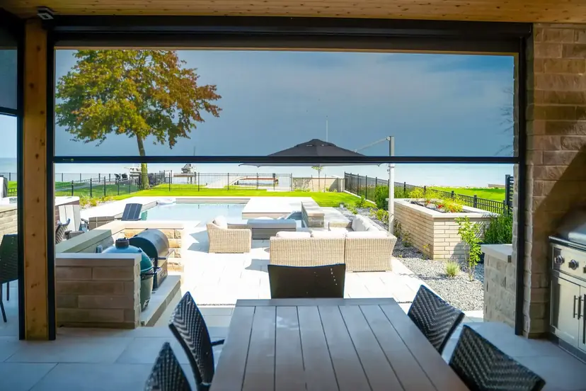 Sunspace retractable screen raised over a patio with a lake view