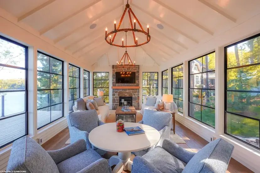 Sunspace sunroom interior with a vaulted white ceiling, iron chandelier and blue seating